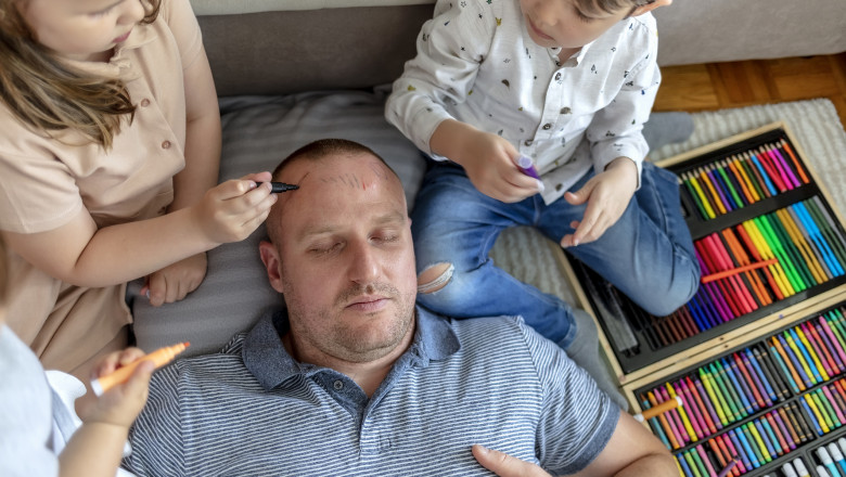 doi copii isi coloreaza pe frunte tatal care doarme