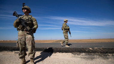 Soldat american care stă pe marginea unui drum în timp ce un altul patrulează