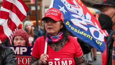 Femeie cu un steag de campanie a lui Trump, cu șapcă și tricou roșii MAGA
