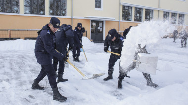 Un detașament de jandarmi intervine pentru degajarea zăpezii din curtea școlii gimnaziale Principesa Margareta, marți, 10 ianuarie 2017.