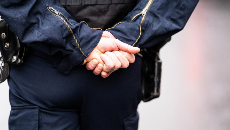 politist francez care sta cu mainile la spate