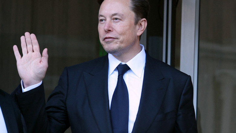 Elon Musk în costum face cu mâna
