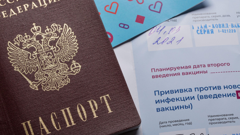 Moscow, Russia - March 31 2021: Extreme close up of Russian passport laying down on COVID-19 vaccination certificate.