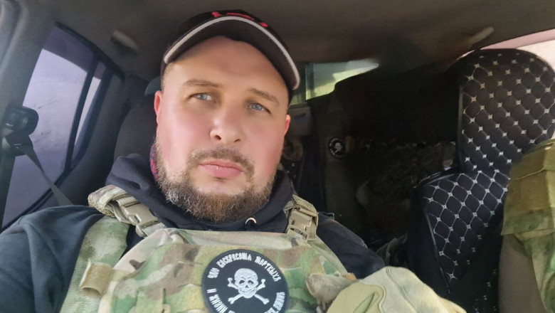 Vladlen Tatarski îmbrăcat într-o uniformă de tip militar pe locul din dreapta al unei mașini