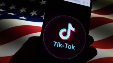 Aplicația TikTok văzută pe un telefon mobil pe fundalul unui steag american.