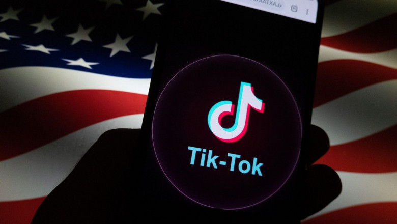 Aplicația TikTok văzută pe un telefon mobil pe fundalul unui steag american.