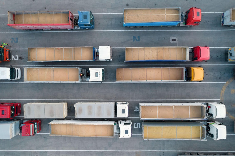 Many trucks are waiting in line for unloading in the port harbor, top view from a quadcopter on trucks loaded with grain. Concept for logistics and fr