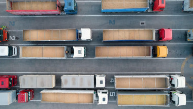 Many trucks are waiting in line for unloading in the port harbor, top view from a quadcopter on trucks loaded with grain. Concept for logistics and fr
