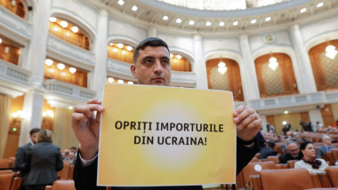 Președintele AUR George Simion ține o pancartă în care cere oprirea importurilor de cereale ucraienne, în Parlamentul României, pe 18 aprile 2023.
