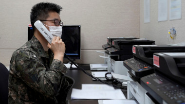 un militar coreean cu mască cu un receptor inscripționat cu un text în limba coreeană