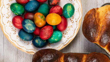 Traditional sweet bread in baking pan and Easter painted eggs, top view.