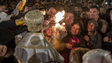 Persoane aprind lumânări la slujba de înviere de la Patriarhia Română, în București, pe 7 aprilie 2018.