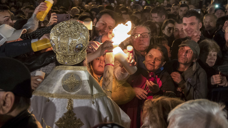 Persoane aprind lumânări la slujba de înviere de la Patriarhia Română, în București, pe 7 aprilie 2018.
