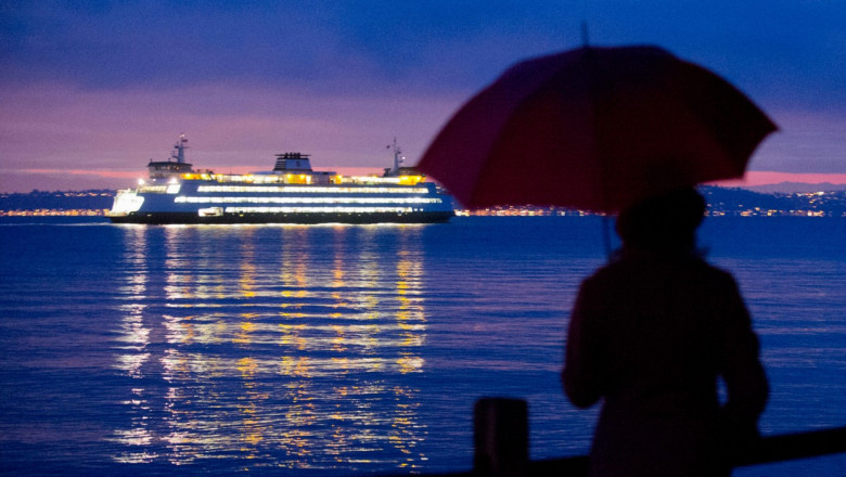 o femeie cu umbrela se uita la o nava de croaziera cu toate luminile aprinse