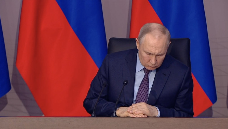 Vladimir Putin cu privirea rătăcită se uită pe masă