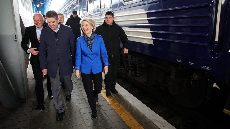 ursula von der leyen imbracata in albastru este inconjurata de barbati pe un peron de gara, langa un tren