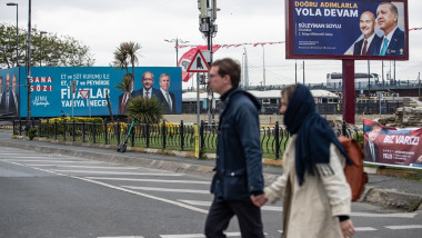 Un cuplu se plimbă pe lângă posterele candidaților la alegerile prezidențiale din Turcia, în Istanbul, pe 12 mai 2023.