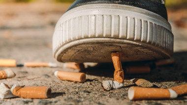 A man puts out a cigarette with his foot. The shoe steps on the cigarette butts. Smoking is injurious to health. Cigarettes