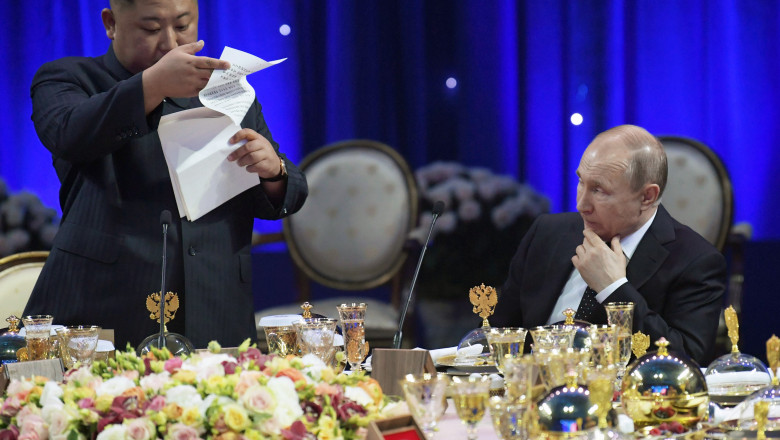 Kim Jong Un îi citește lui Putin de pe o foaie la o masă plină de mâncare