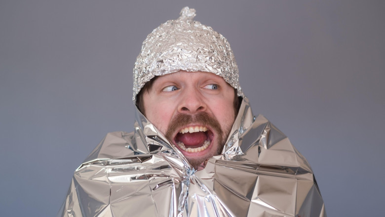 Young man in a cap of foil being afraid and stressed.