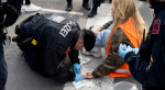 Polițiști austrieci în timp ce încerca să o elibereze pe o activistă lipită cu adeziv de asfalt.