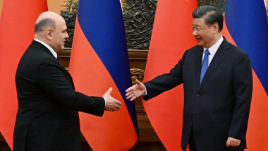Mikhail Mishustin (left) and Xi Jinping shake hands