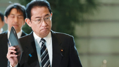 premierul Fumio Kishida merge pe un hol cu o agenda in mana