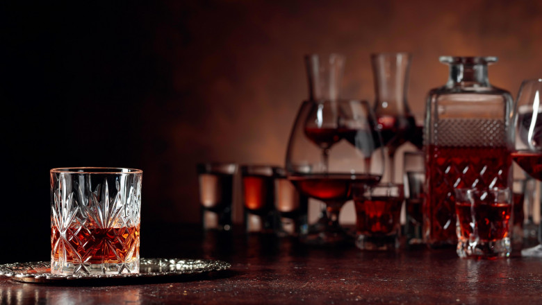 Set of strong alcoholic beverages in glasses on a brown background. Focus on a glass of whiskey.