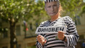 Protestatar îmbrăcat într-o uniformă de prizonier cu fața lui Vladimir Putin, ținând un banner cu un cuvânt în limba rusă