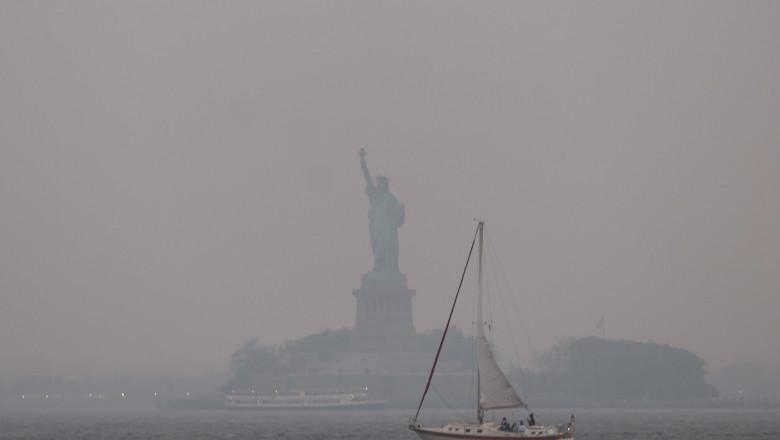 Statuia Libertății din NEw York este învăluită de un fum portocaliu, pe 6 iunie, din cauza incendiilor de vegetație din Canada.