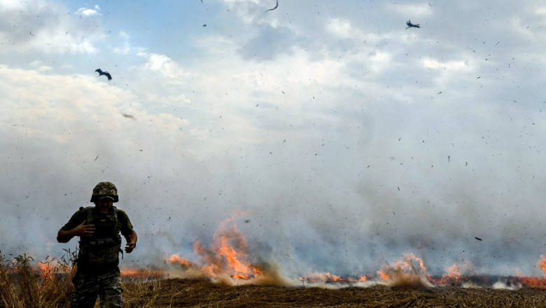 Un militar aleargă pe un câmp din Zaporojie, Ucraina, unde vegetația este aprinsă, pe 17 iulie 2022.