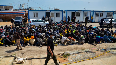 Migranți așezați pe pământ după ce au fost recuperați de pe mare de Garda de Coastă din Tunisia pe 8 iunie 2023.