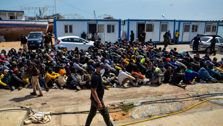 Migranți așezați pe pământ după ce au fost recuperați de pe mare de Garda de Coastă din Tunisia pe 8 iunie 2023.