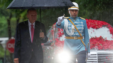 erfogan isi tine umbrela in ploaie, un soldat din garda de onoare in spatele lui