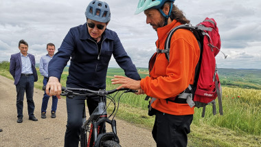 geoana cu casca de bicicleta si ochelari sta pe bicicleta, un biciclist ii explica comenzile