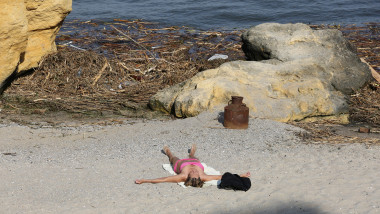 A woman seen sunbathing on the beach of Otrada near the garbage nailed to the shore