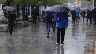 Persoane folosesc umbrele pentru a se apăra de ploaie, în București, joi 4 mai 2023.