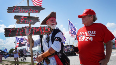 bărbat îmbrăcat în pirat și un altul într-un tricou și șapcă roșie cu blazonul campaniei lui Trump