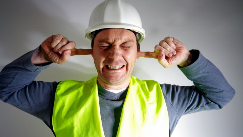 Muncitor care își astupă urechile din cauza zgomotului