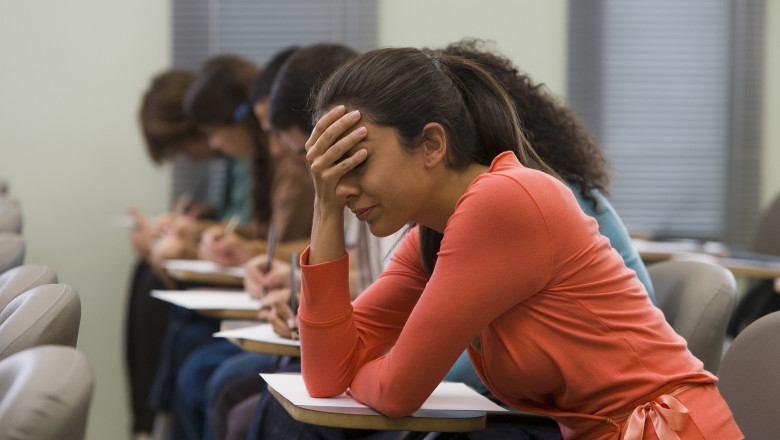 o eleva imbracata in rosu isi duce mana la cap in timpul unui examen
