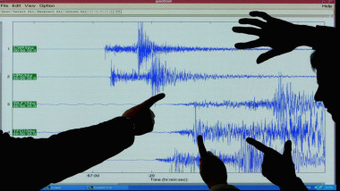 Mâini arată spre datele înregistrate de un seismograf