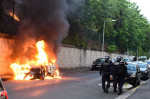 jandarmi francezi trec pe lângă o mașină în flăcări