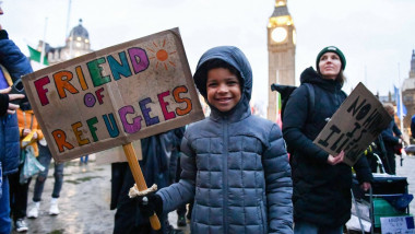 Copil cu o pancartă cu un mesaj pro-refugiați cu Big Ben pe fundal