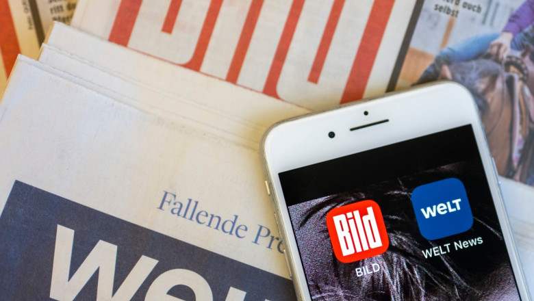Ziarele tiparite Bild și Die Welt peste care e așezat un telefon mobil pe ecranul căruia se văd aplicațiile online ale celor două publicații, fotografiate pe 23 ianuarie 2023