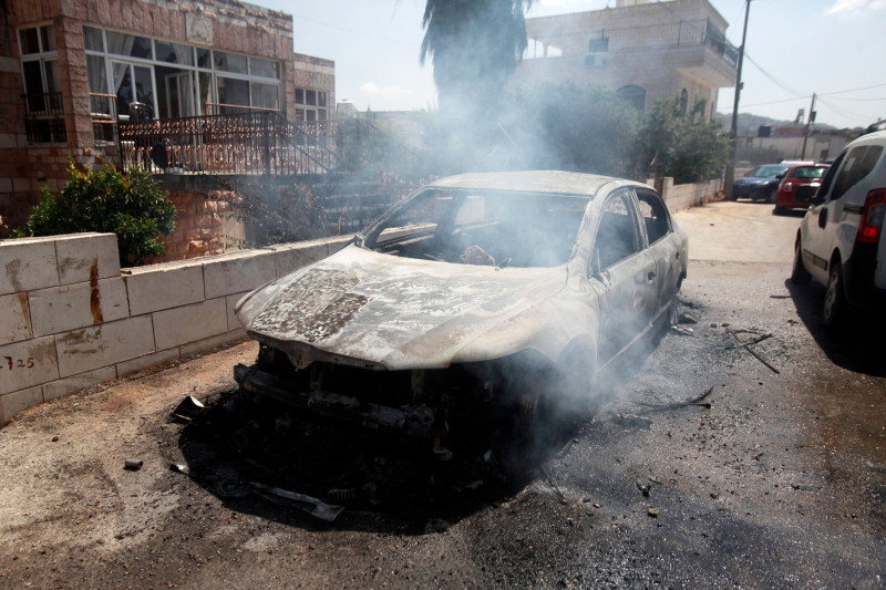 A car set on fire by Israeli settlers is pictured in front of a house in Turmus Aya, near the West Bank city of Ramallah, Ramallah, West Bank, Palestinian Territory - 21 Jun 2023