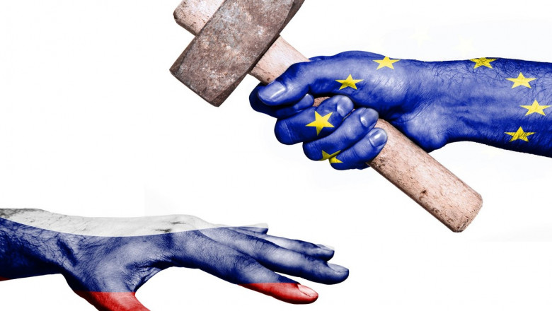 Flag of European Union overprinted on a hand holding a heavy hammer hitting a hand representing the Russia. Conceptual image for