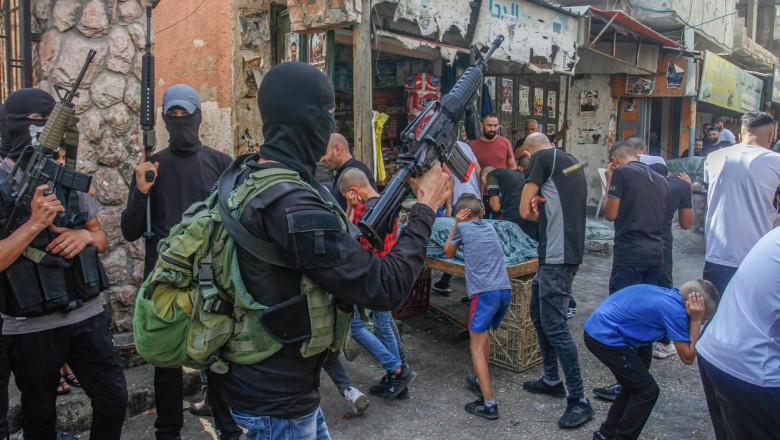 Bărbați palestinieni înarmați și cu cagule trag focuri de armă în aer în semn de protest față de un raid israelian în Cisiordania, pe 1 septembrie 2022.