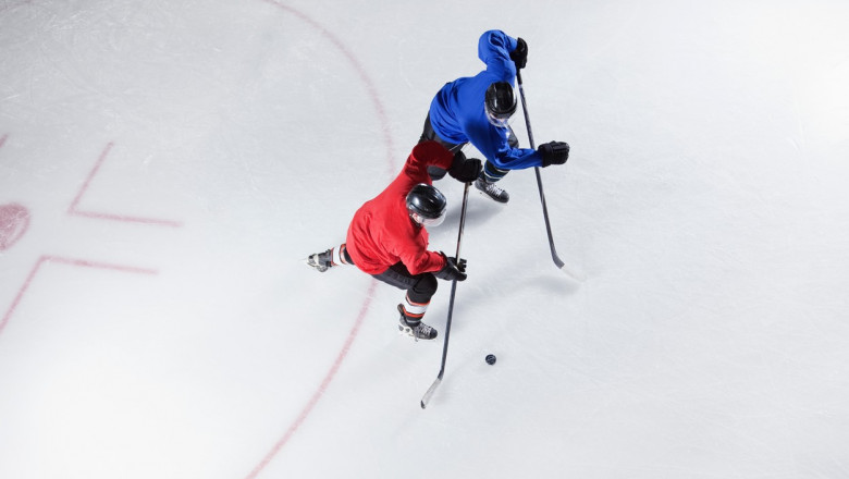 jucători de hochei pe gheață, unul îmbrăcat în roșu și altul în albastru