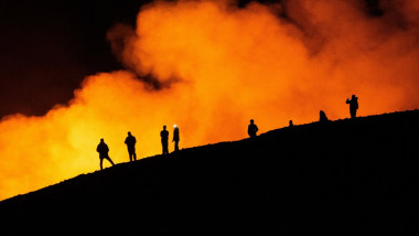 oameni pe un vulcan in timpul unei eruptii