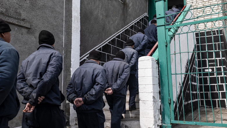 A group of Russian soldiers captured during the war in Ukraine lines up towards stairs in a Ukrainian prison